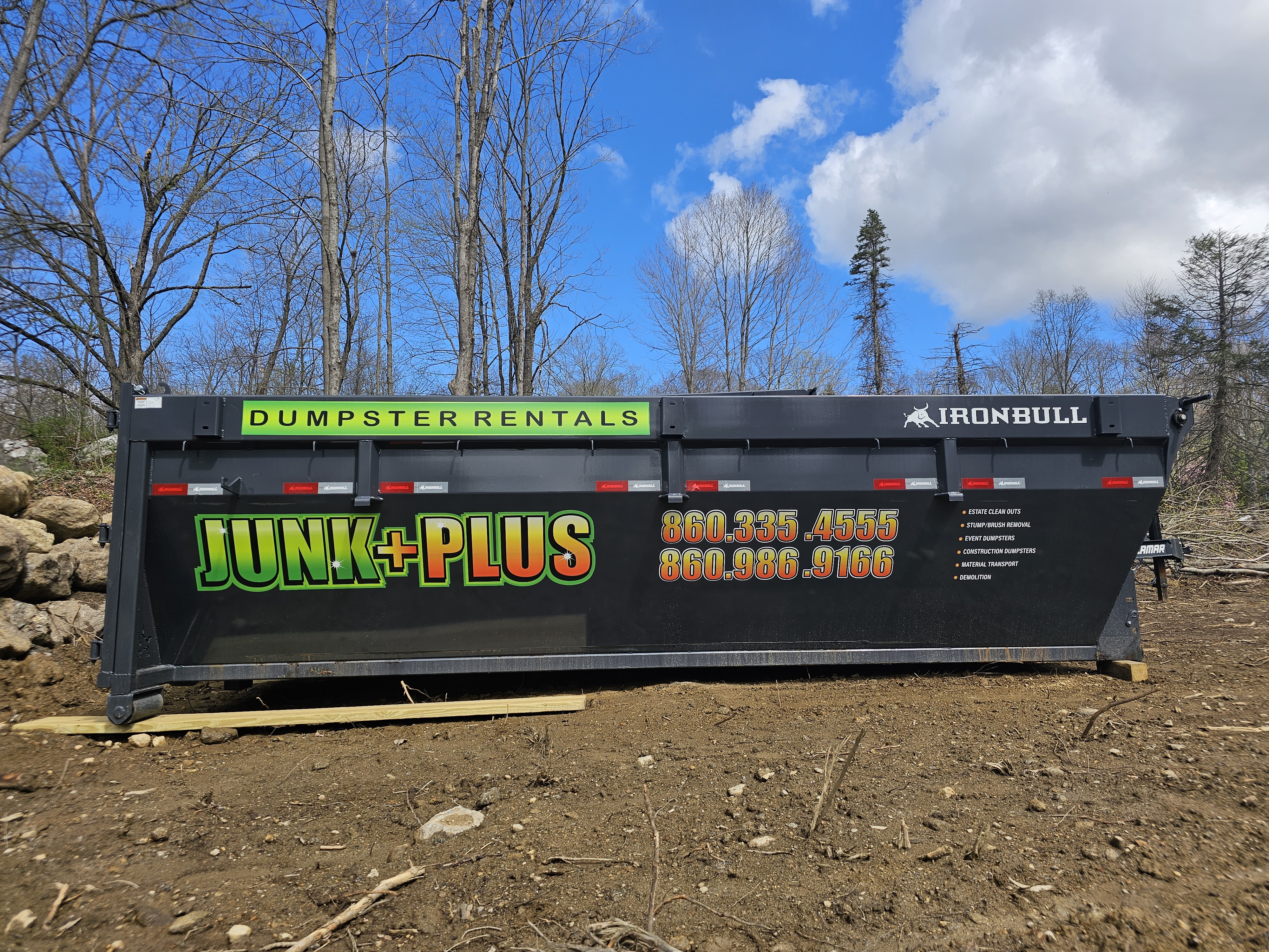 Junk Plus roll-off dumpster staged on protective boards.